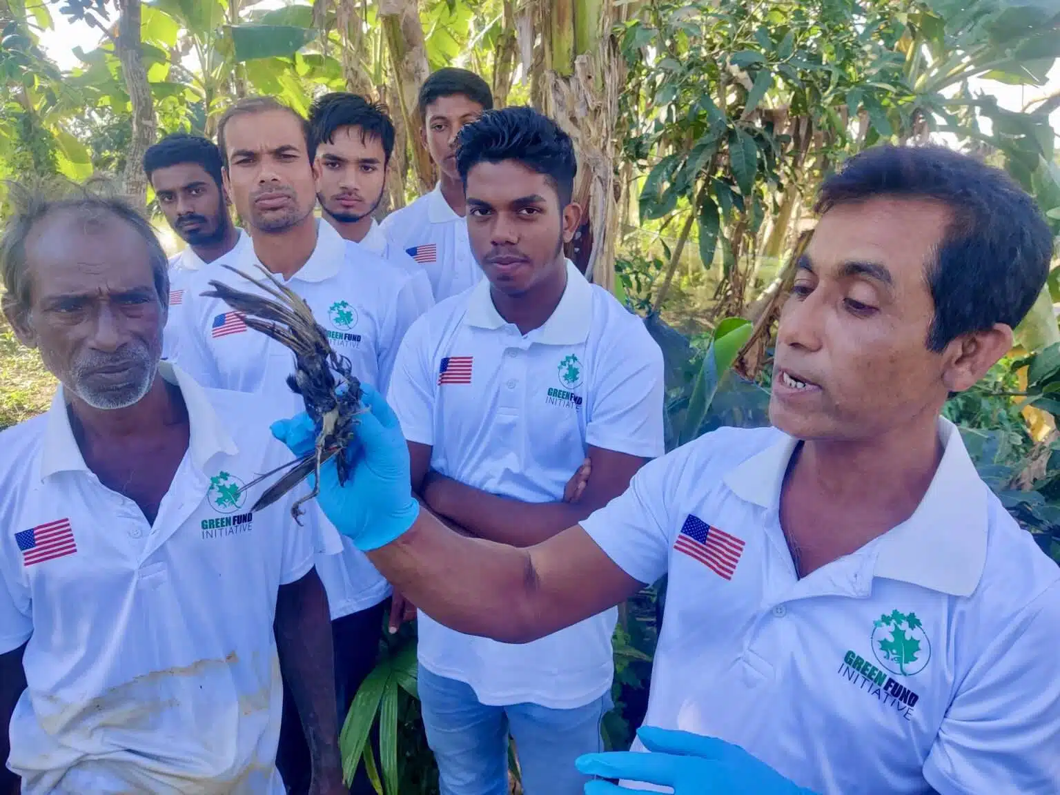 GFI volunteers holding a rescued bird while villagers look on