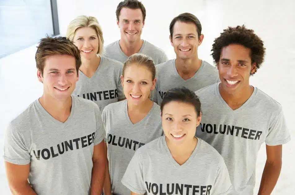 A group of smiling volunteers in matching volunteer T-shirts