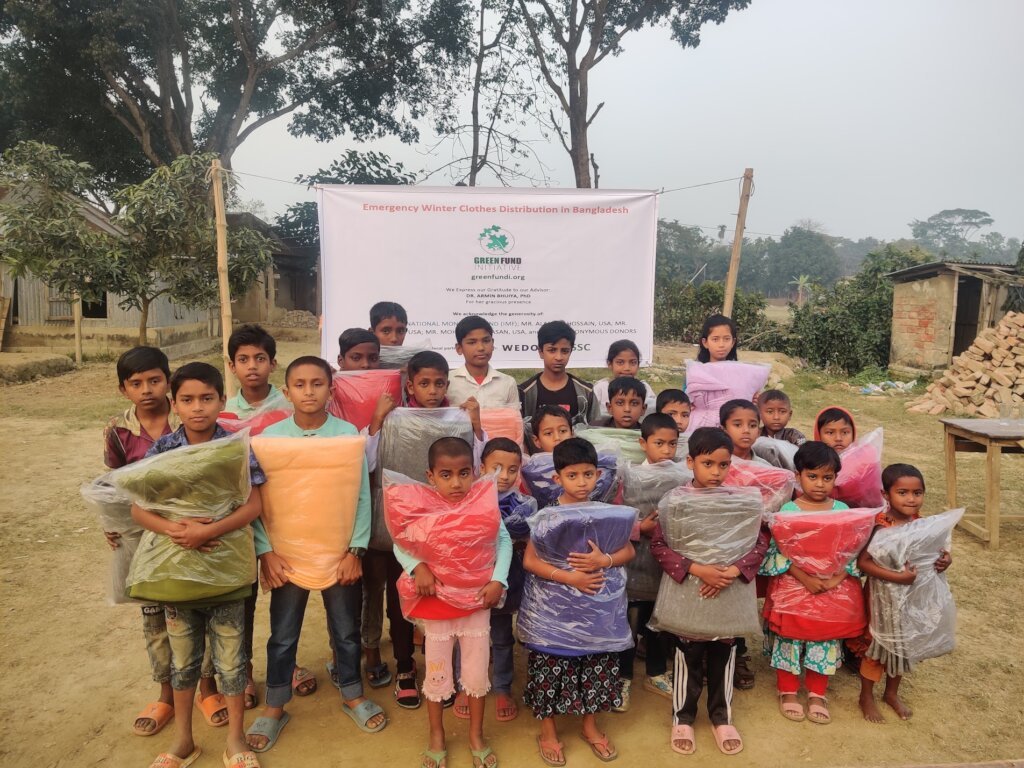 A large group of children holding the supply packs they received, standing in front of a GFI banner