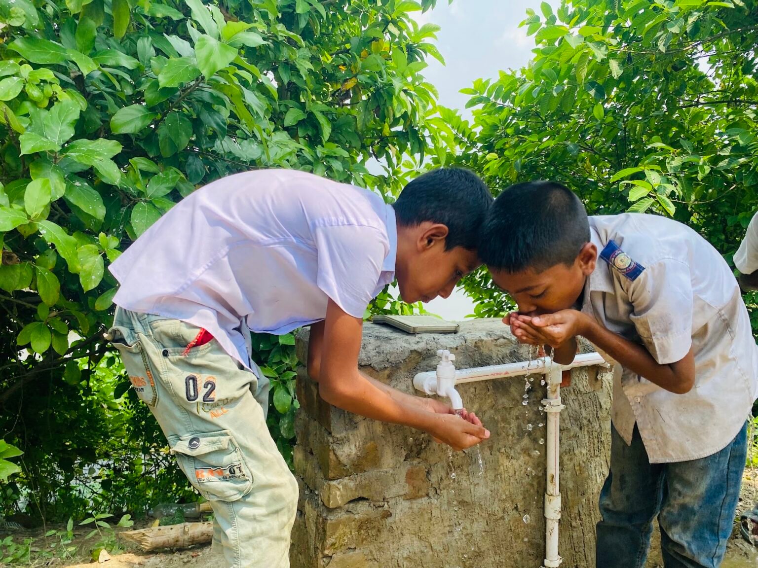 Schoolboys drinking clean water from the taps of a new water point