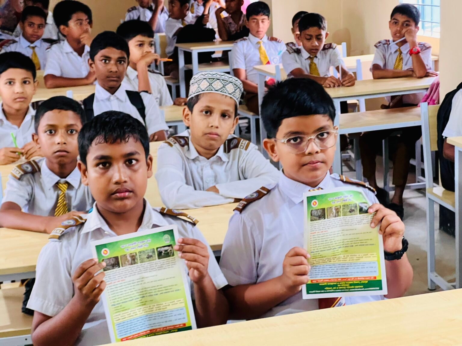 Schoolchildren in a classroom holding conservation leaflets